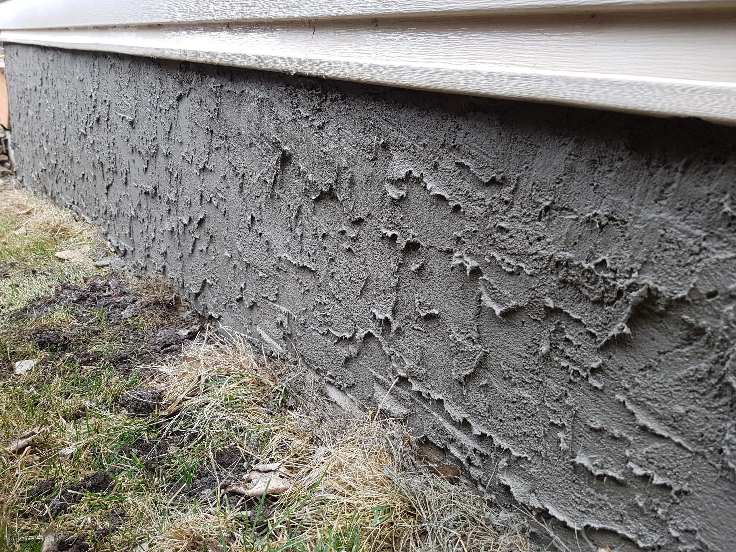 Freshly applied textured parging on a Calgary home foundation